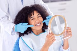 woman smiling while looking in hand mirror