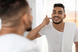 man looking at his smile in the mirror